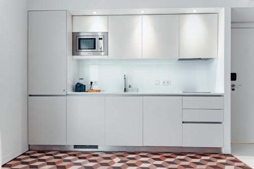 a kitchen with white cabinets and a microwave at 54 São Paulo - Exclusive Apartment Hotel in Lisbon