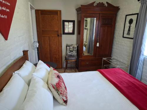 a bedroom with a bed with white sheets and a mirror at Rietfontein farmstay in Prince Albert