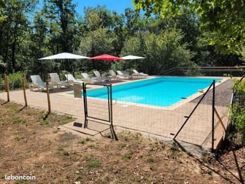 a swimming pool with chairs and umbrellas next to at Gîte Le Colombet in Audrix