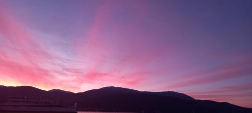 a sunset with a rainbow in the sky over mountains at Nightflower rooms sami in Sami