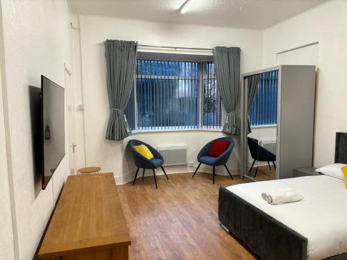 a bedroom with a bed and two chairs and a table at Del Apartments in Warrington