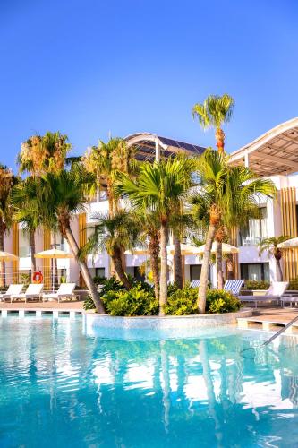 a swimming pool with palm trees in front of a building at Radisson Beach Resort Larnaca in Larnaca