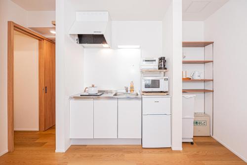 a white kitchen with a sink and a microwave at Kamakura no Nikki in Kamakura