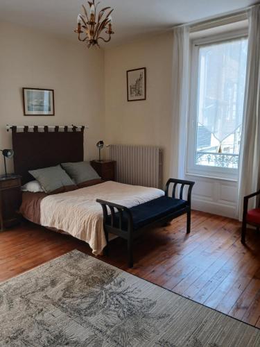 a bedroom with a bed with a bench and a window at Villa Toscane in Saint-Germain-Lembron