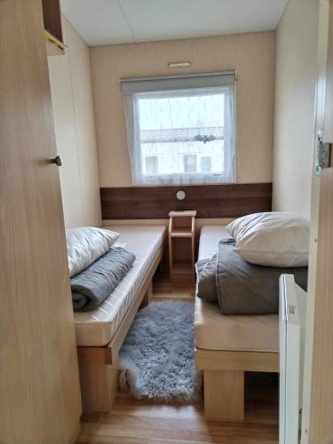 deux lits dans une petite pièce avec une fenêtre dans l'établissement Mobil home 6 personnes au Camping paradis du Quinquis, à Clohars-Carnoët