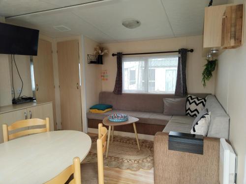 un petit salon avec un canapé et une table dans l'établissement Mobil home 6 personnes au Camping paradis du Quinquis, à Clohars-Carnoët