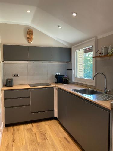 d'une cuisine avec des placards gris, un évier et une fenêtre. dans l'établissement Appartement dans maison de ville, proche stade de France et Salon du Bourget, à La Courneuve