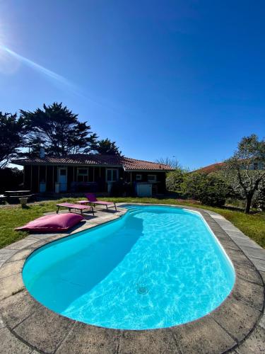 une piscine avec une maison en arrière-plan dans l'établissement Bourdaines - Villa entre océan et forêt, à Seignosse