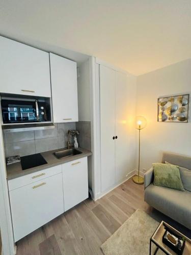 une cuisine avec des placards blancs et un canapé dans le salon dans l'établissement Tour Eiffel Bir Hakeim 2, à Paris
