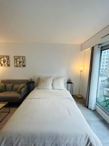 Cette chambre comprend un grand lit blanc et un canapé. dans l'établissement Tour Eiffel Bir Hakeim 2, à Paris