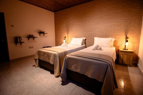 a bedroom with two beds and a brick wall at Pine View Boutique Hotel Adults Only in Saittas