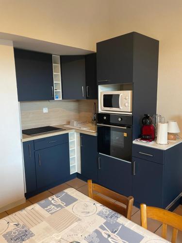 une petite cuisine avec des placards bleus et une table avec une table dans l'établissement Maison bord de mer pour 2 à 6 pers, à La Tranche-sur-Mer