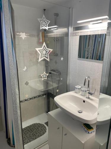La salle de bains est pourvue d'un lavabo et d'une douche avec des étoiles sur le mur. dans l'établissement Maison bord de mer pour 2 à 6 pers, à La Tranche-sur-Mer