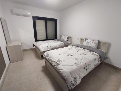 a bedroom with two beds and a window at 3bedroom chalet swan lake North coast- 388B in Zāwiyat al ‘Awwāmah