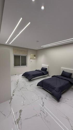 a room with two beds on a marble floor at شقة بأثاث فُندقي in Al Madinah