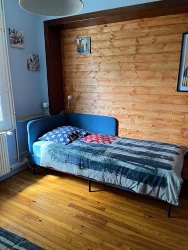 a bed in a room with a wooden wall at Le Trankiloup in Grézac