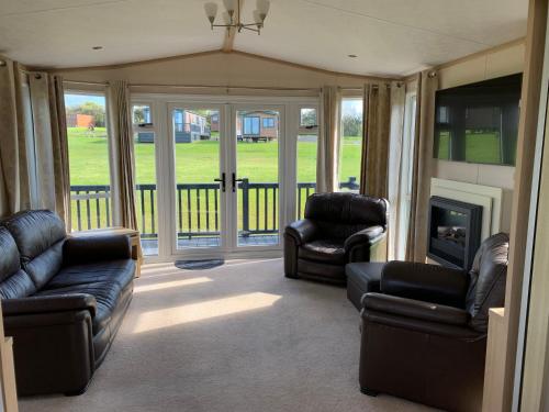 a living room with leather furniture and a fireplace at 37 Atlantic Way in West Down