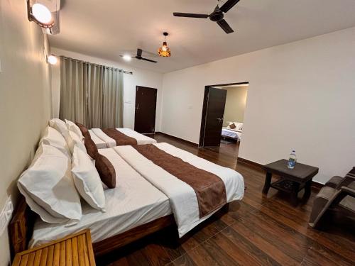 a bedroom with three beds and a ceiling fan at Grand Narmada Jungle Homestay Resort-Bandhavgarh in Tāla