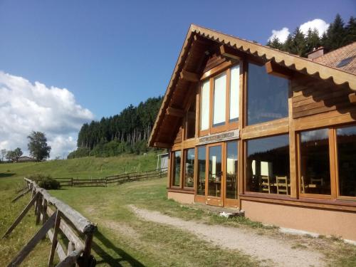 a wooden building with a fence next to a field at Ferme auberge des Cimes in Urbeis