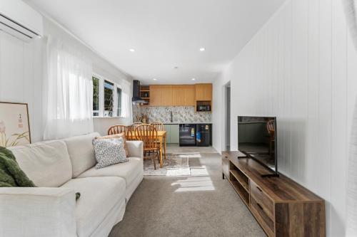 a living room with a couch and a television at Pine Hill Cottage -Auckland in Tuakau