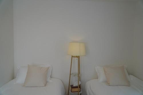 two beds in a room with white walls and a lamp at Kamakura no Nikki in Kamakura