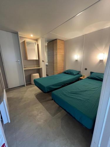 - 2 lits dans une petite chambre avec des draps verts dans l'établissement Mobile Home 6 personnes, à Seignosse