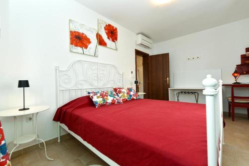 a bedroom with a white bed with a red bedspread at Charming apartment with balcony and pool in Peroj
