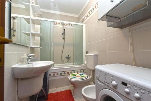 a bathroom with a sink toilet and a washing machine at Charming apartment with balcony and pool in Peroj
