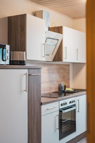 KönigsbrückにあるCASALOTTI Ferienwohnung Königsbrückの白いキャビネットとコンロ付きオーブンを備えたキッチン