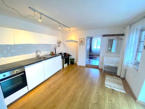 a kitchen with white cabinets and a wooden floor at Winzerhaus Rossatz in Rossatz