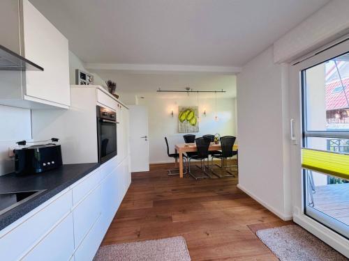 a kitchen with white cabinets and a table with chairs at seeglueck RHEINPARADIES - Geräumige Ferienwohnung mit Wasserblick Balkon Parkplatz und Zentrumsnähe am Rheinufer in Konstanz in Konstanz
