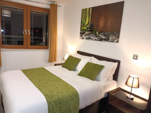 a bedroom with a large bed with two green pillows at KCS Birmingham City Apartment with Balcony/Parking in Birmingham