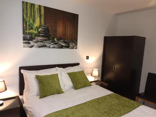 a bedroom with a bed with green and white pillows at KCS Birmingham City Apartment with Balcony/Parking in Birmingham