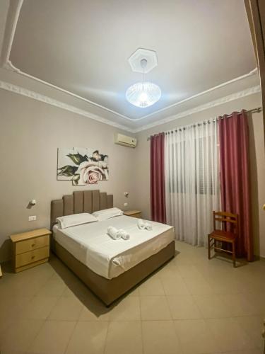 a bedroom with a bed and a chandelier at Oaz Guest House Durres in Durrës