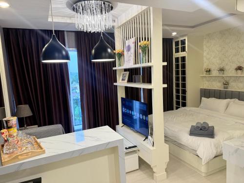 a bedroom with a bed and a desk with a television at The Patio bangsaen miracle sea Top floor in Ban Chek