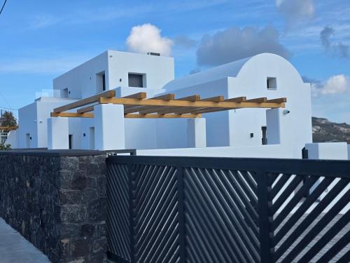 a white house with a black fence at Santorini Ethereal Blue Suites in Pirgos