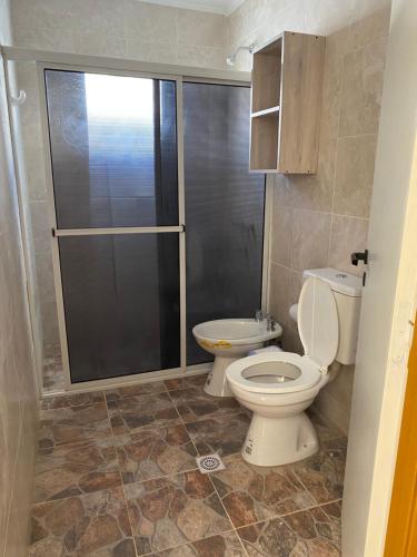 a bathroom with a toilet and a glass shower at Departamentos Belgrano in San Luis
