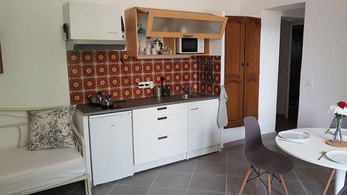 a kitchen with white cabinets and a table and a chair at GitesLuberon 2 F2 in Charleval