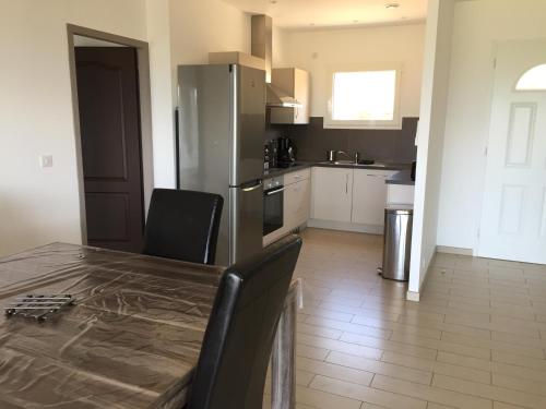 une cuisine avec une table avec des chaises et un réfrigérateur dans l'établissement Locations I Carboni - villa 2 chambres, à Sollacaro