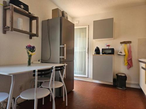 Il comprend une cuisine équipée d'un réfrigérateur, d'une table et de chaises. dans l'établissement L'authentique - Roquille - Histoire de clés, au Cap d'Agde