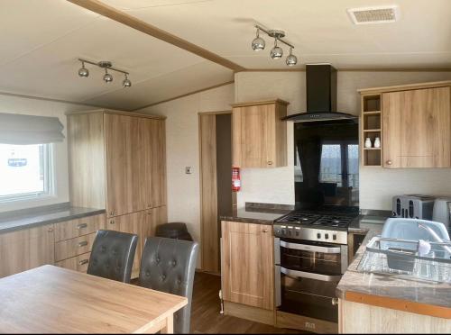 a kitchen with wooden cabinets and a stove top oven at Seaview Caravan, Perran Sands in Perranporth