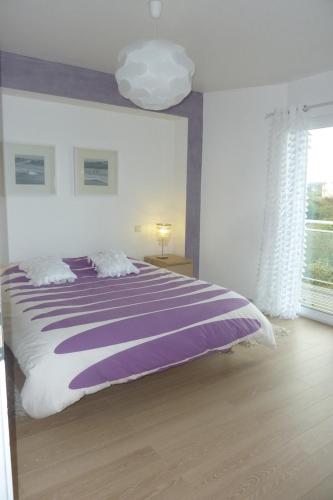 une chambre avec un grand lit avec une couverture violette dans l'établissement Villa with terrace and garden, à La Méaugon