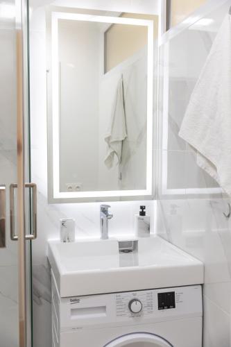 La salle de bains blanche est pourvue d'un lavabo et d'un lave-linge. dans l'établissement Appartement avec climatisation, à 900 m de la plage, à Fréjus