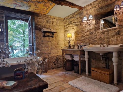 La salle de bains en pierre est pourvue d'un lavabo et d'une baignoire. dans l'établissement Moulin du XIIIe siècle pour 2 personnes, à Bozouls