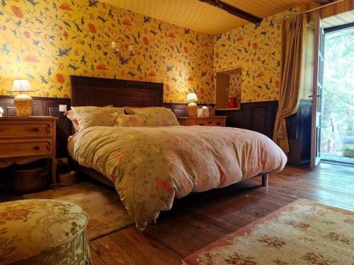 - une chambre avec un grand lit et du papier peint floral dans l'établissement Moulin du XIIIe siècle pour 2 personnes, à Bozouls
