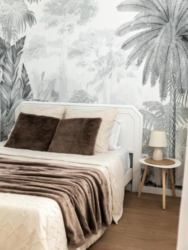 - une chambre avec un lit blanc et du papier peint tropical dans l'établissement Appartement avec climatisation, à 900 m de la plage, à Fréjus