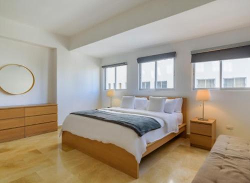 Un dormitorio con una cama grande y dos ventanas. en Escape 3BR Apartment in the Heart of Piantini Nightlife, en Santo Domingo