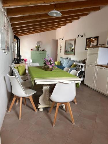 a dining room with a green table and white chairs at Antico casale Sofia in Sortino