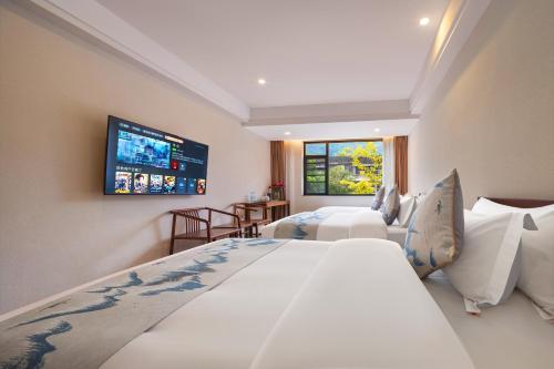 a bedroom with two beds and a flat screen tv at Mare Nubium Resort in Zhangjiajie