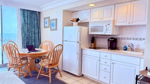 a kitchen with a table and a white refrigerator at Breathtaking OCEAN FRONT Condo in Daytona Beach in Daytona Beach